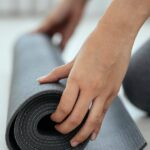 crop female holding rolled mat on floor